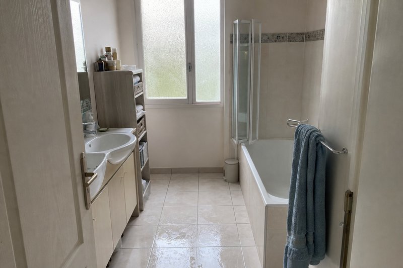 Salle de bain domestique — carrelage humide, porte-serviettes décoratif, aucun point d'appui solide