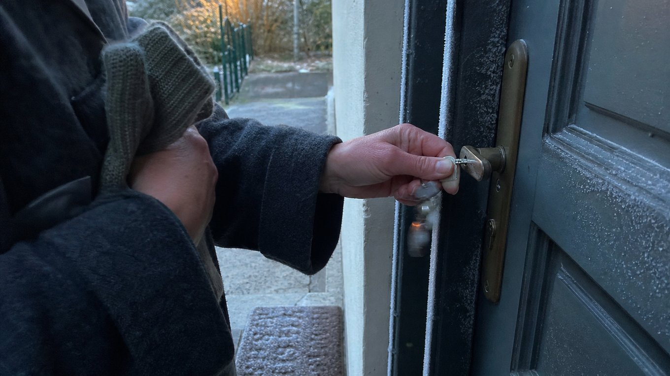 Une main nue, gelée, essaie de fermer la porte à clé, le gant épais retiré