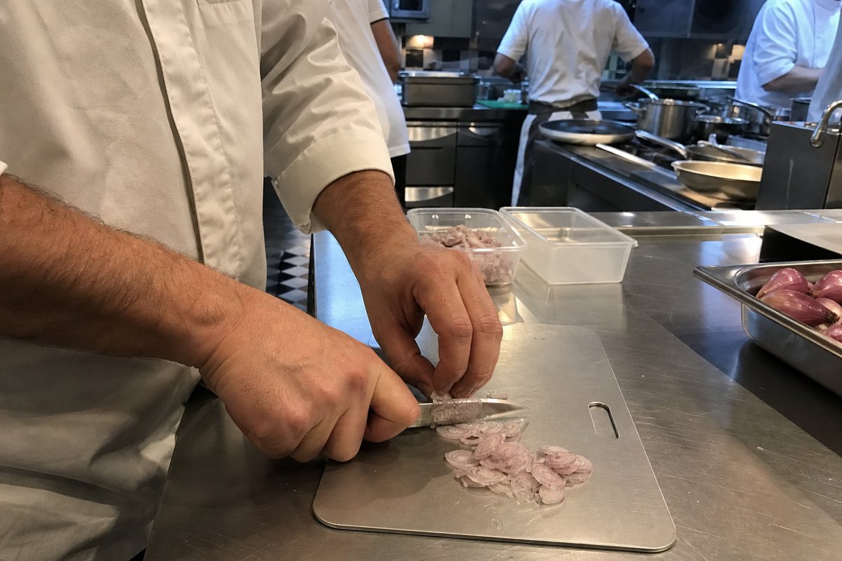 Un chef travaille sur une planche à découper en titane dans une cuisine professionnelle