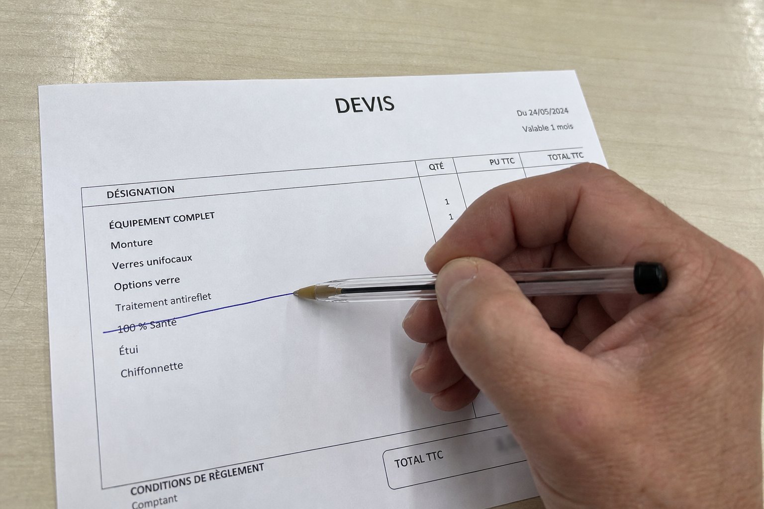 Un stylo barre la ligne 100 % Santé sur un devis d'opticien posé sur un comptoir